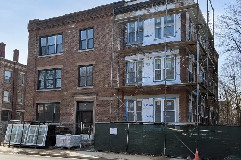 Brick walk-up apartment building with scaffolding and new windows being installed